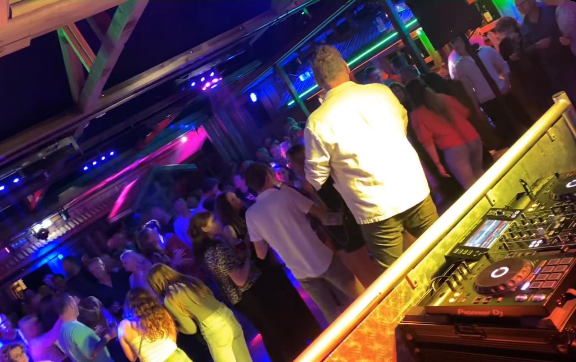 Publiek voor de DJ-booth in een volle feestzaal